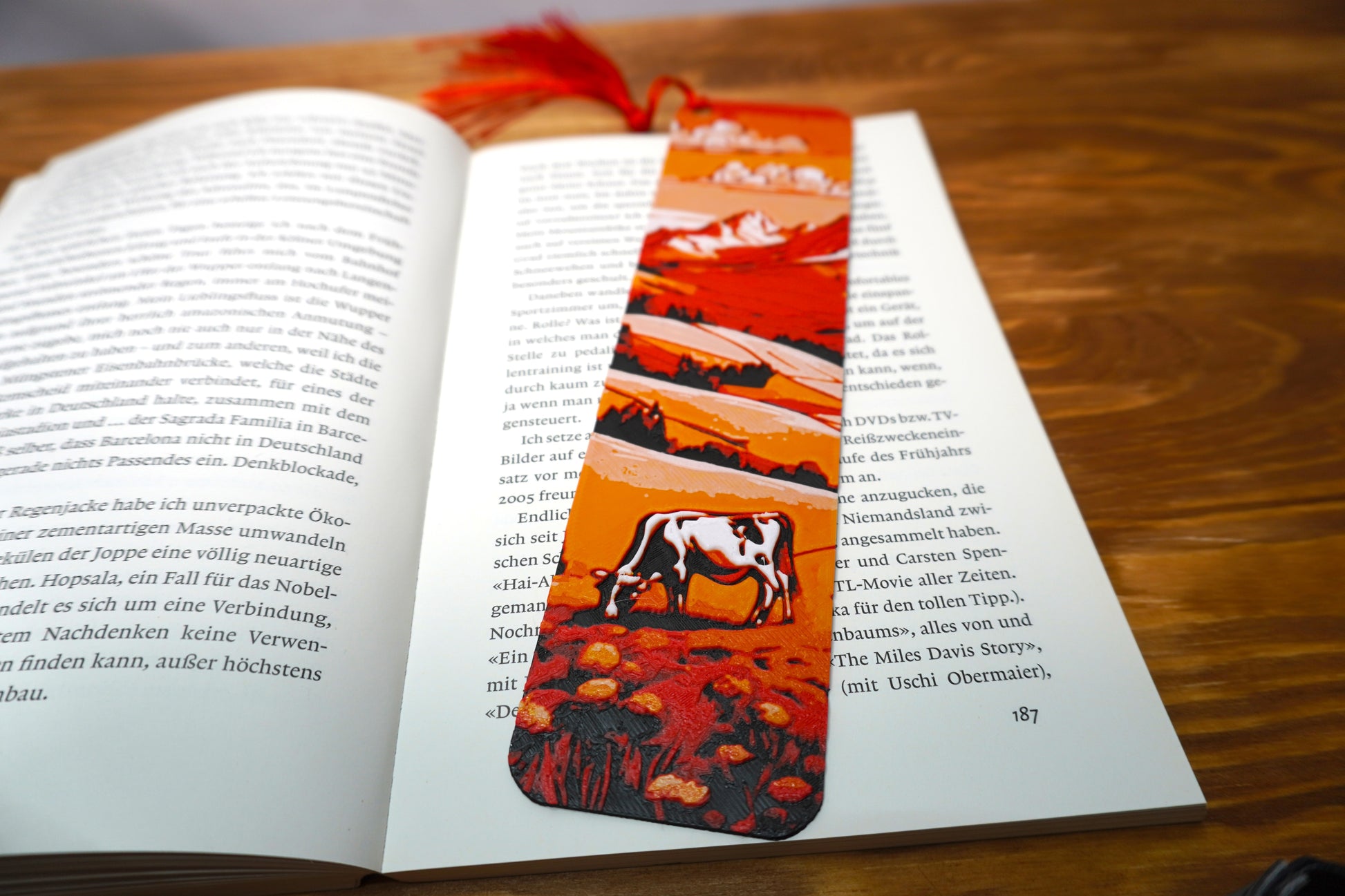 Lesezeichen mit Panorama schneebedeckter Berge und grasender Kuh, wahlweise mit Quaste