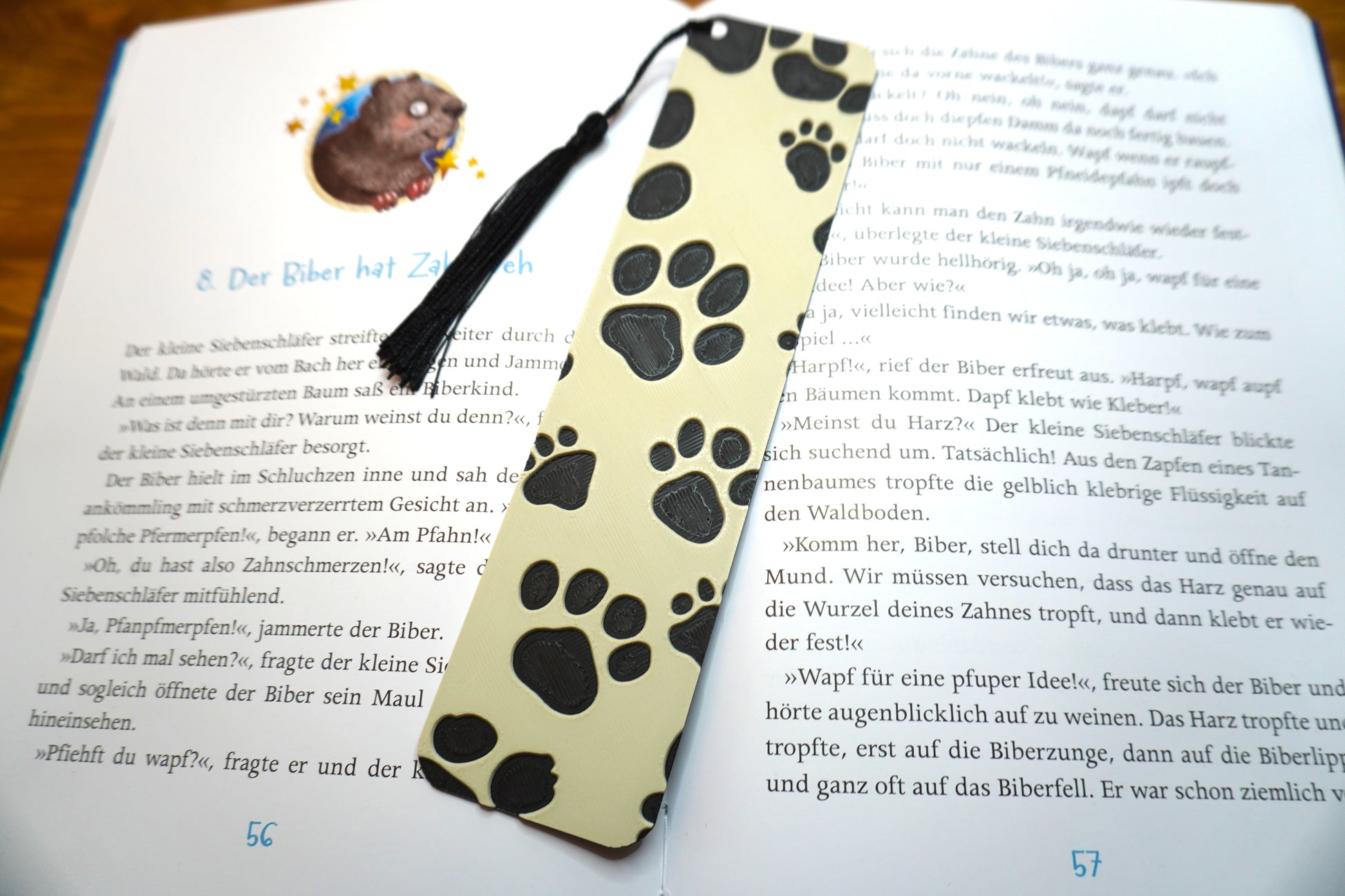 Lesezeichen mit schwarzem Hundepfoten-Design auf beigem Hintergrund, wahlweise mit Quaste